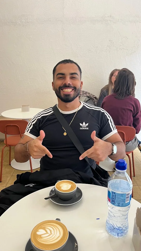 Leonardo sorrindo e apontando para um flat white no Dale Café, em Salamanca